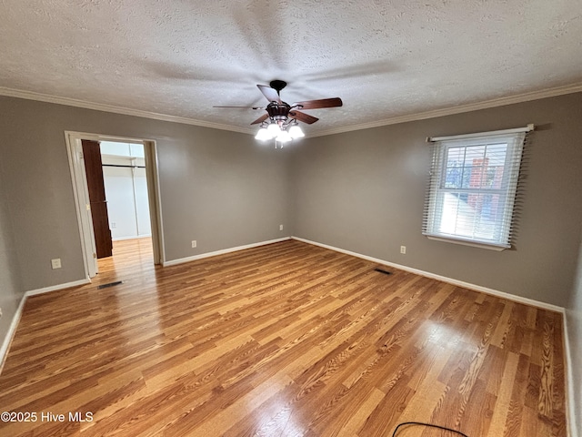 spare room featuring ornamental molding, a textured ceiling, and light hardwood / wood-style flooring