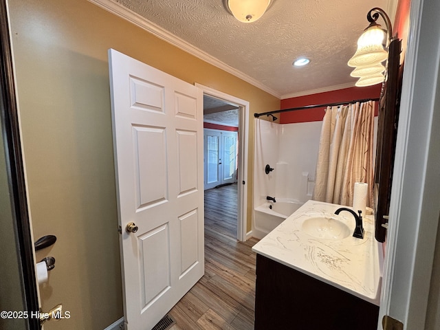 bathroom with shower / bath combo, hardwood / wood-style floors, vanity, ornamental molding, and a textured ceiling