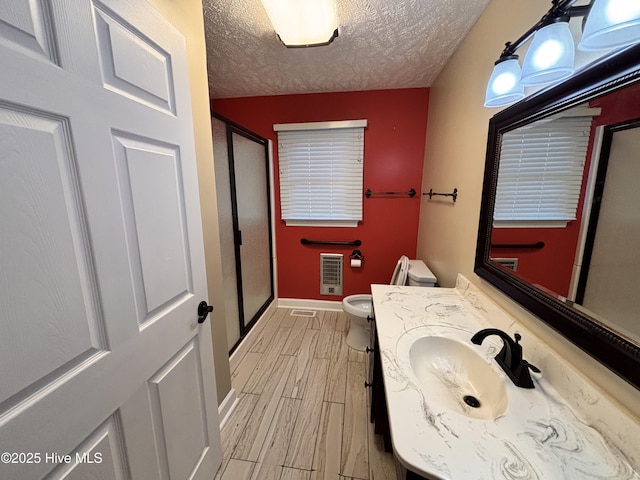 bathroom with vanity, wood-type flooring, a textured ceiling, toilet, and walk in shower