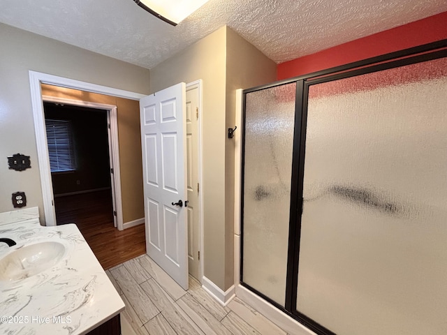 bathroom featuring a shower with door, vanity, and a textured ceiling