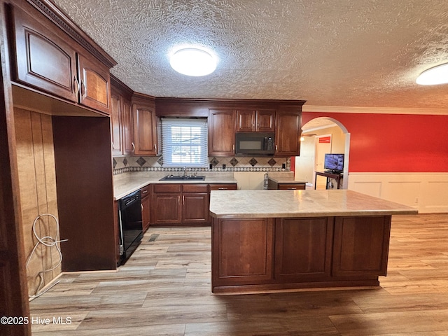 kitchen featuring sink, light hardwood / wood-style flooring, ornamental molding, decorative backsplash, and black appliances