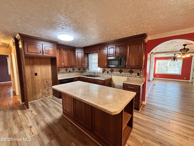 kitchen featuring crown molding, ceiling fan, a center island, tasteful backsplash, and light hardwood / wood-style floors