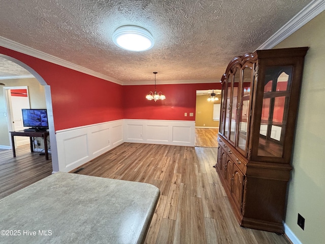 dining room featuring an inviting chandelier, hardwood / wood-style floors, crown molding, and a textured ceiling