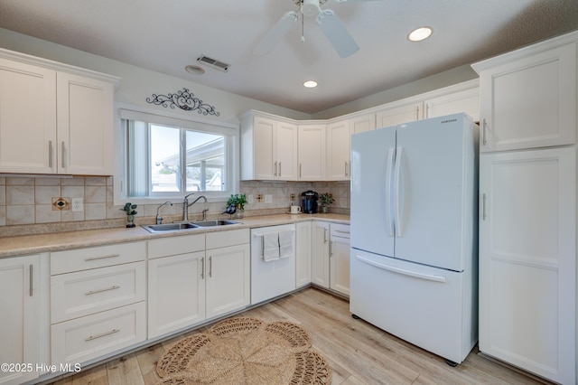 kitchen with sink, white cabinetry, tasteful backsplash, light hardwood / wood-style flooring, and white appliances