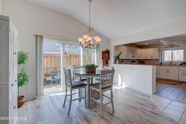 dining room with lofted ceiling, sink, ceiling fan with notable chandelier, and light hardwood / wood-style flooring