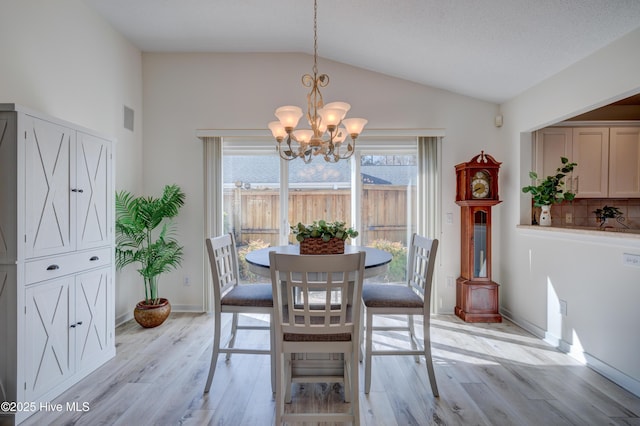 dining space featuring vaulted ceiling, an inviting chandelier, and light hardwood / wood-style floors