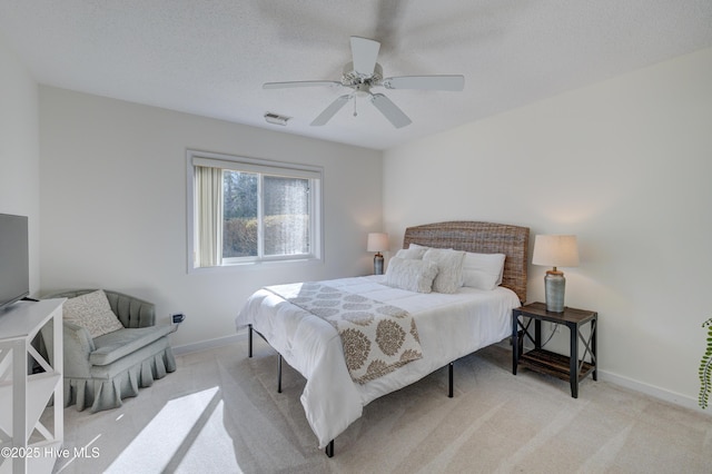 bedroom with light carpet, ceiling fan, and a textured ceiling