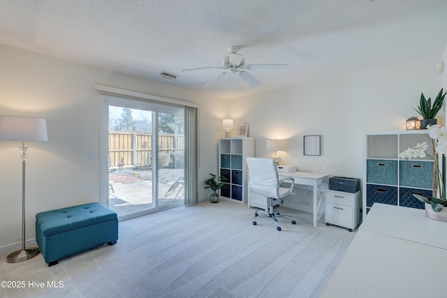 carpeted office featuring ceiling fan and a textured ceiling