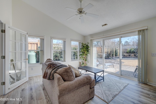 living room featuring ceiling fan, vaulted ceiling, light hardwood / wood-style floors, and a textured ceiling