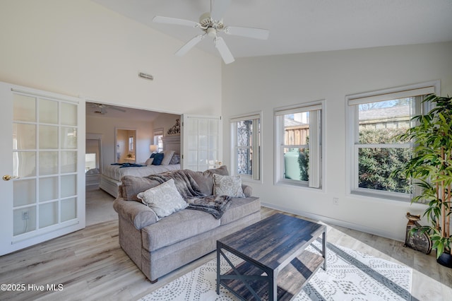 living room featuring light hardwood / wood-style flooring, high vaulted ceiling, and ceiling fan