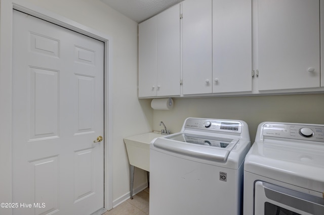 washroom with independent washer and dryer, light tile patterned floors, and cabinets