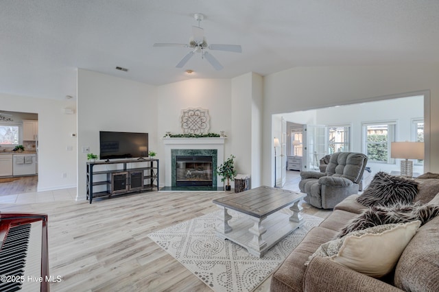 living room featuring lofted ceiling, a high end fireplace, plenty of natural light, and light hardwood / wood-style floors