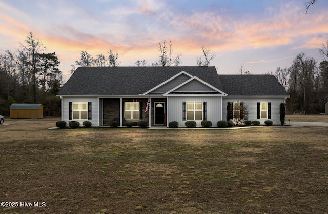 single story home featuring a storage shed and a lawn