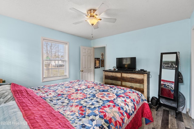 bedroom with dark hardwood / wood-style flooring, ceiling fan, and a textured ceiling