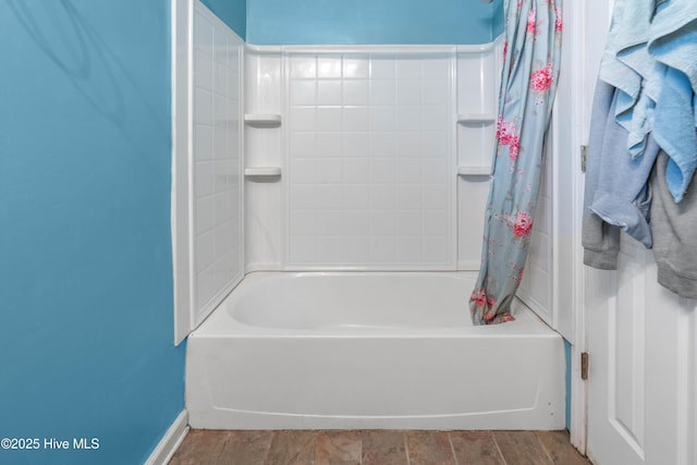 bathroom with hardwood / wood-style flooring and shower / bath combo with shower curtain