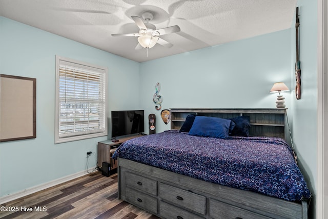 bedroom with ceiling fan, dark wood-type flooring, and a textured ceiling