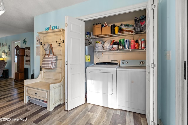 laundry area with separate washer and dryer, wood-type flooring, water heater, and a textured ceiling