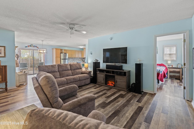 living room with hardwood / wood-style flooring, ceiling fan, and a textured ceiling