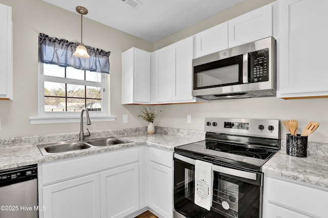 kitchen featuring white cabinetry, stainless steel appliances, decorative light fixtures, and sink