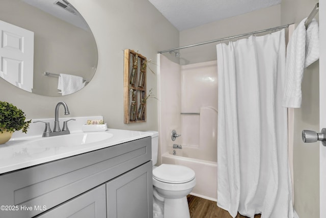 full bathroom with hardwood / wood-style floors, vanity, toilet, shower / bathtub combination with curtain, and a textured ceiling