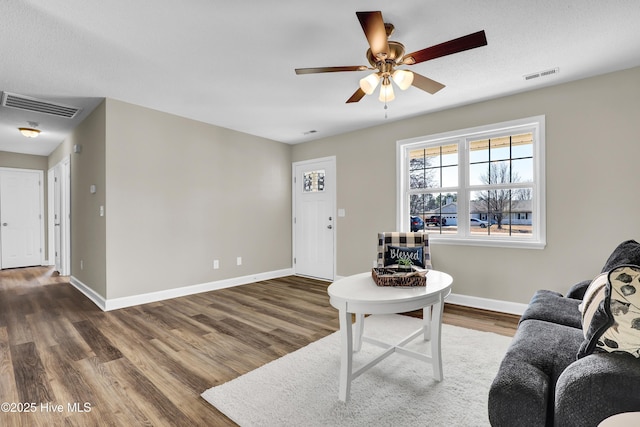 living room with dark wood-type flooring, a textured ceiling, and ceiling fan