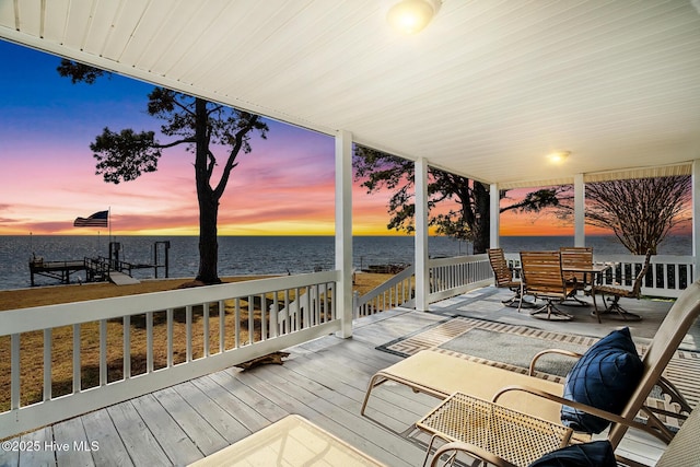 deck at dusk featuring a water view