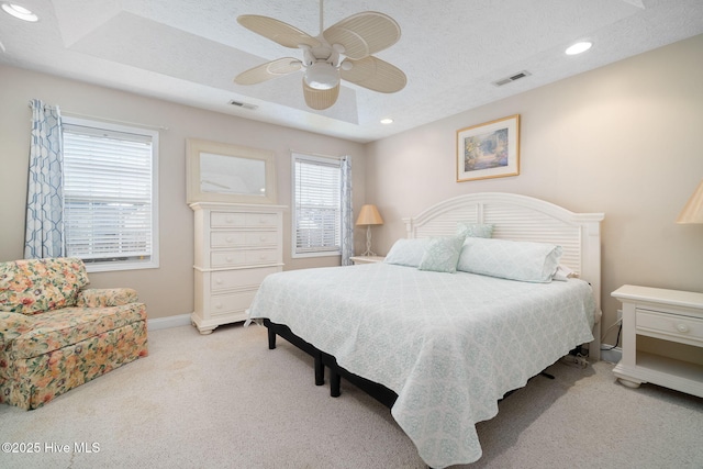 bedroom featuring ceiling fan, light colored carpet, and a textured ceiling