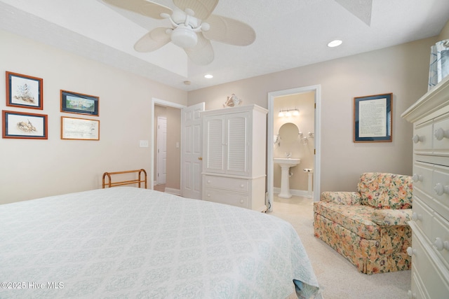 bedroom featuring a textured ceiling, light colored carpet, ceiling fan, and ensuite bathroom