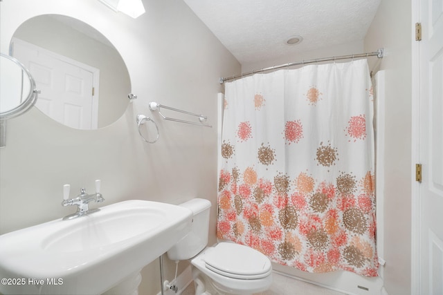 bathroom with toilet, curtained shower, sink, and a textured ceiling