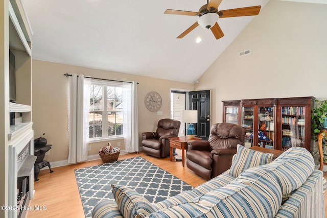 living room with ceiling fan, high vaulted ceiling, and light hardwood / wood-style floors