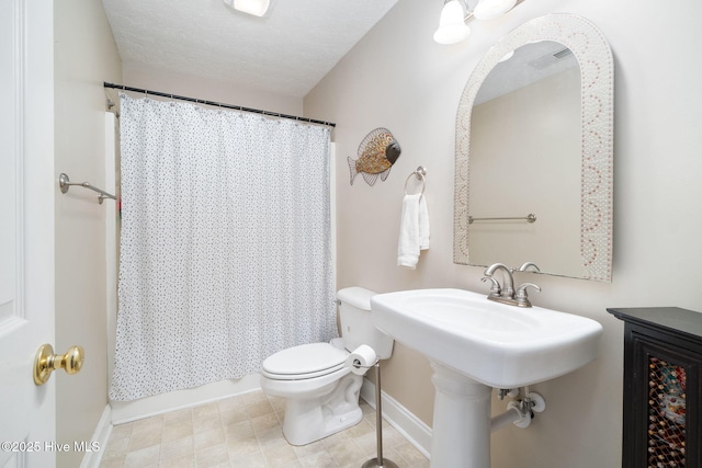 bathroom featuring toilet, a textured ceiling, and shower / bath combo