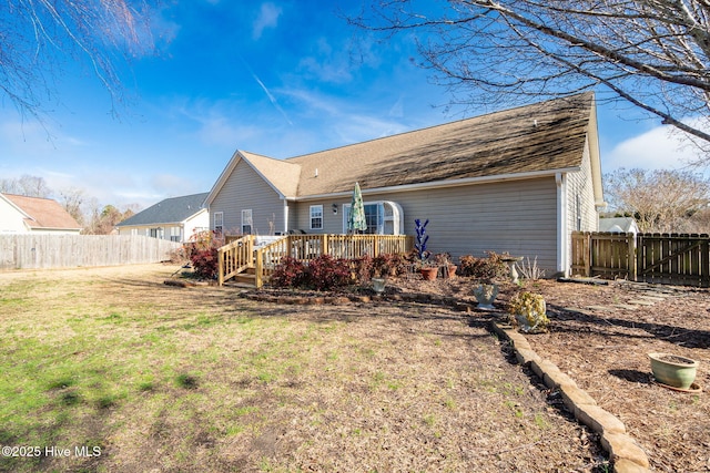 rear view of house featuring a wooden deck and a yard