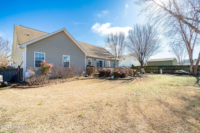 rear view of house featuring a deck and a lawn