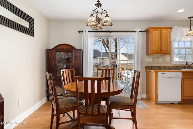 dining area with a notable chandelier, sink, and light wood-type flooring