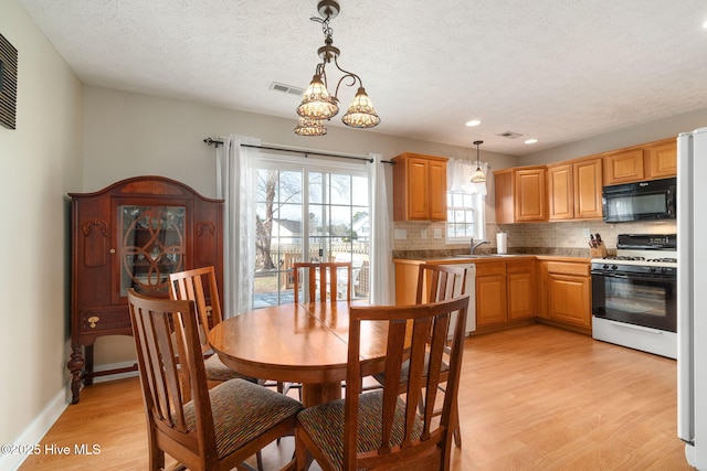 dining area with sink, a textured ceiling, and light wood-type flooring