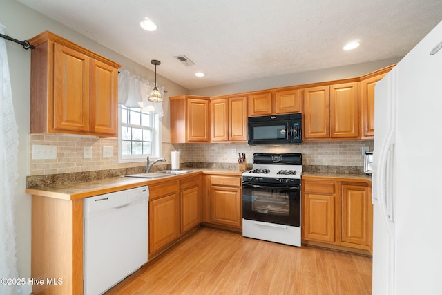 kitchen with sink, white appliances, light hardwood / wood-style flooring, hanging light fixtures, and decorative backsplash