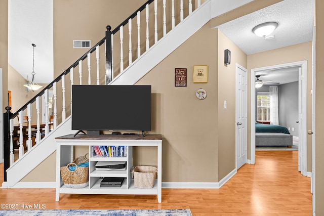 staircase with ceiling fan, wood-type flooring, and a textured ceiling