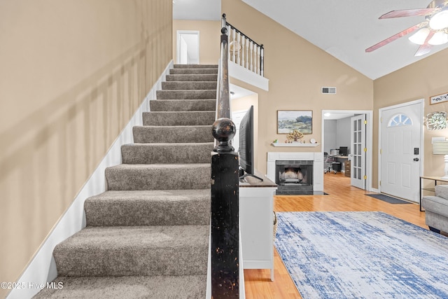 staircase with high vaulted ceiling, hardwood / wood-style floors, and ceiling fan