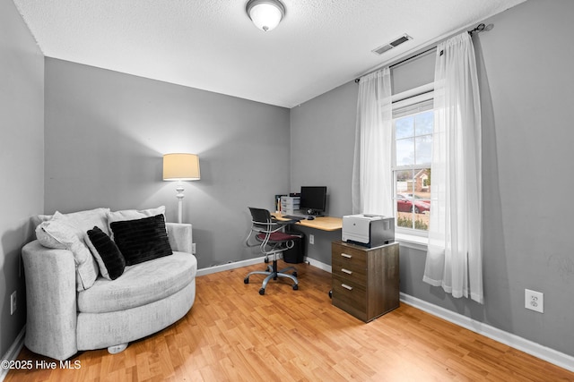 home office featuring a textured ceiling and light hardwood / wood-style floors