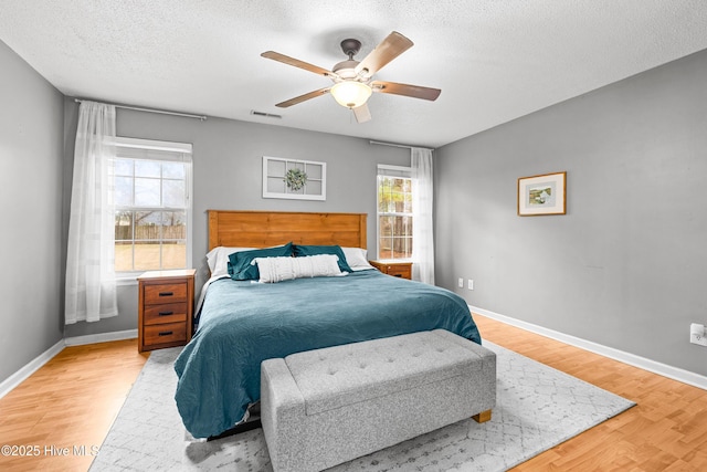 bedroom with ceiling fan, a textured ceiling, and light wood-type flooring