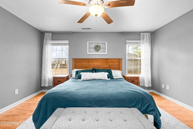 bedroom with ceiling fan, a textured ceiling, and light wood-type flooring