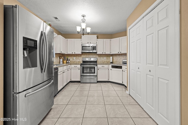 kitchen featuring white cabinetry, tasteful backsplash, light tile patterned floors, appliances with stainless steel finishes, and a notable chandelier