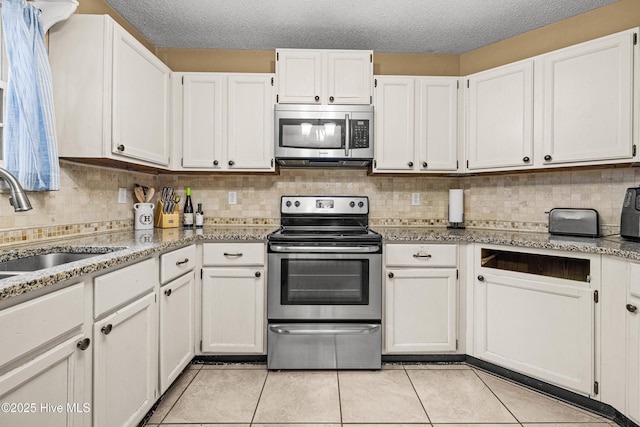 kitchen featuring appliances with stainless steel finishes, light stone countertops, sink, and white cabinets