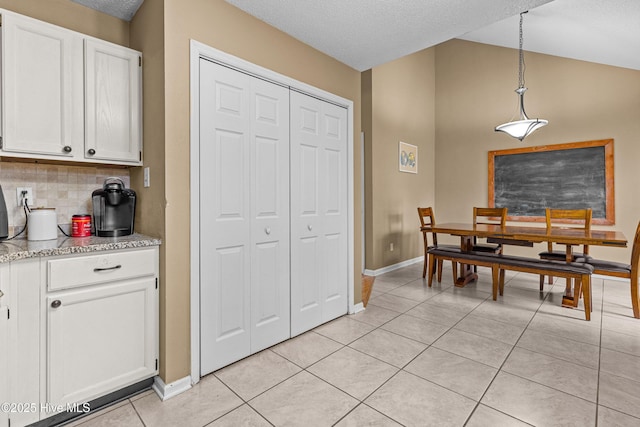 tiled dining space featuring lofted ceiling and a textured ceiling