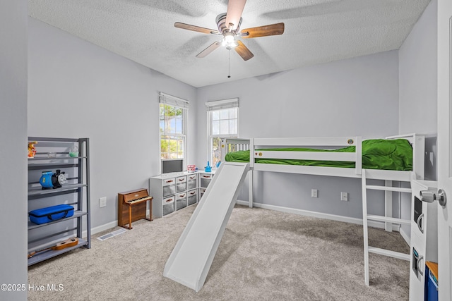 bedroom with ceiling fan, light colored carpet, and a textured ceiling