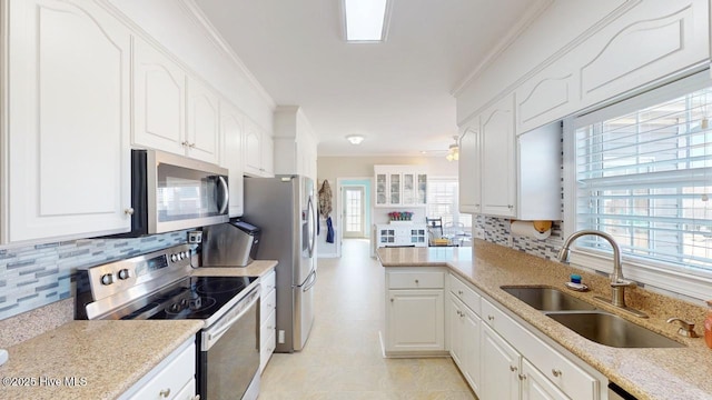 kitchen with appliances with stainless steel finishes, tasteful backsplash, white cabinetry, sink, and ornamental molding