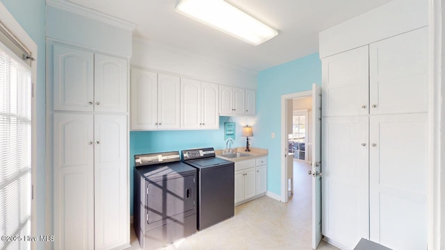 clothes washing area with cabinets, washing machine and clothes dryer, and sink