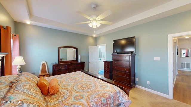 bedroom with a tray ceiling, light colored carpet, and ceiling fan