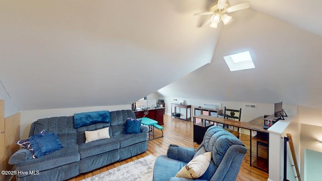 living room with lofted ceiling with skylight and light hardwood / wood-style floors