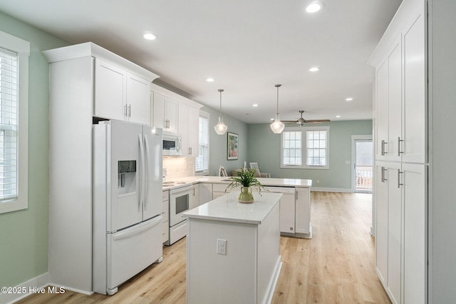 kitchen featuring a center island, kitchen peninsula, pendant lighting, white appliances, and white cabinets